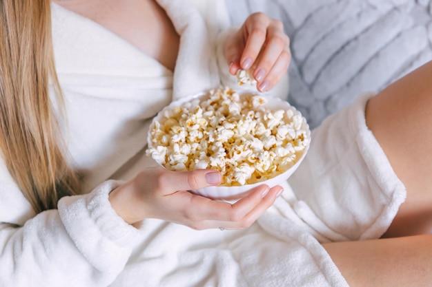 Chiuda in su delle mani della donna che prendono il popcorn dalla ciotola