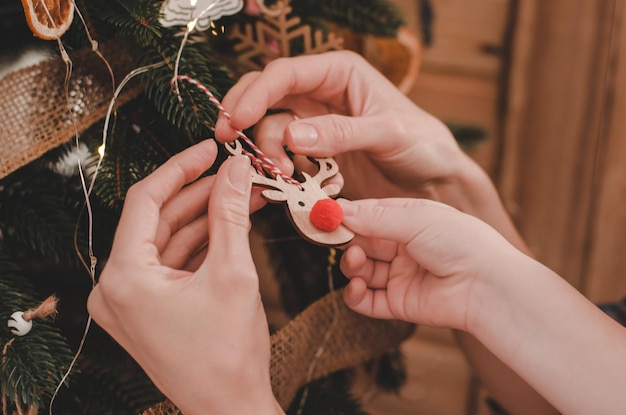 Chiuda in su delle mani della madre e del figlio che decorano l'albero di Natale