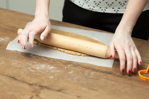 Chiuda in su delle mani femminili che producono i biscotti dalla pasta fresca a casa