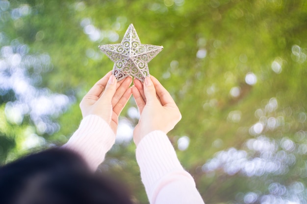 Chiuda in su delle mani femminili che tengono le decorazioni di natale, una piccola stella.