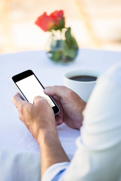 Chiuda in su delle mani maschili utilizzando lo smartphone