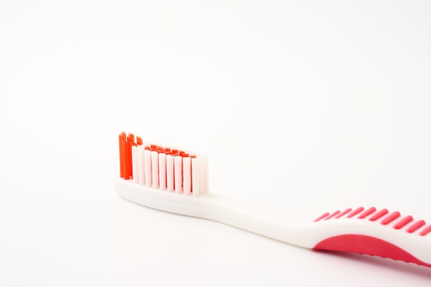 Chiuda in su dello spazzolino da denti su una priorità bassa bianca.