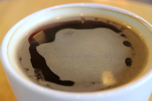 Chiuda in su di caffè nero caldo in una tazza bianca con strato sottile di forma