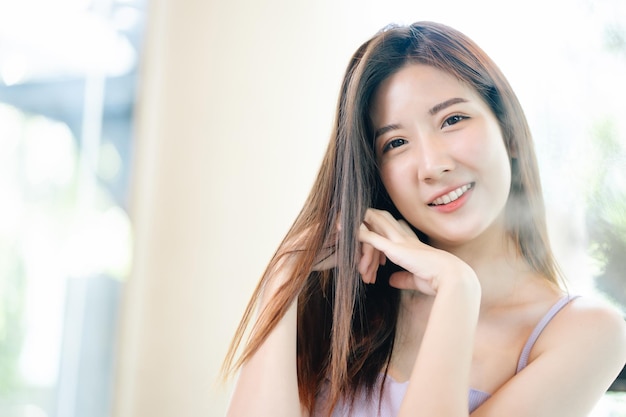 Chiuda in su di giovane bella donna asiatica con le spalle nude piacevoli di smileshows larghe vestite