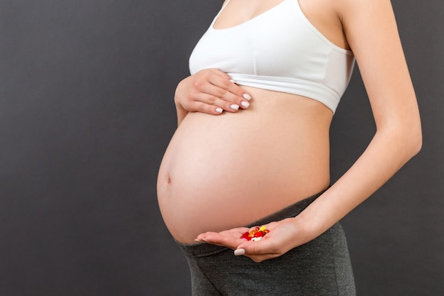 Chiuda in su di un mucchio delle pillole in mano della donna incinta a priorità bassa variopinta con lo spazio della copia. Concetto di assistenza sanitaria