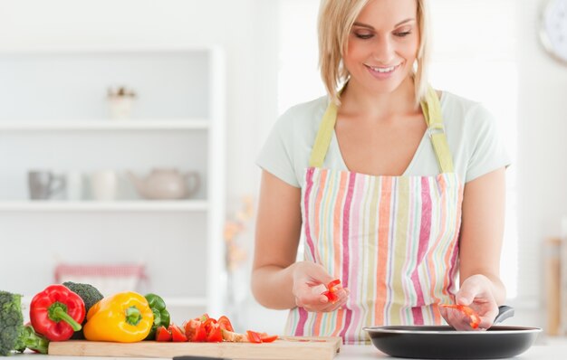 Chiuda in su di una donna che frigge i peperoni