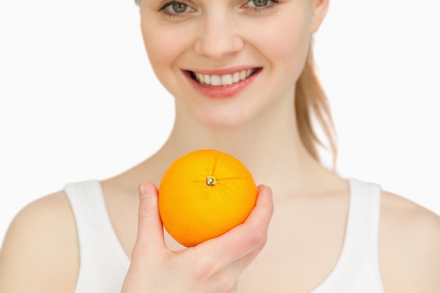 Chiuda in su di una donna che tiene un&#39;arancia mentre sorridendo