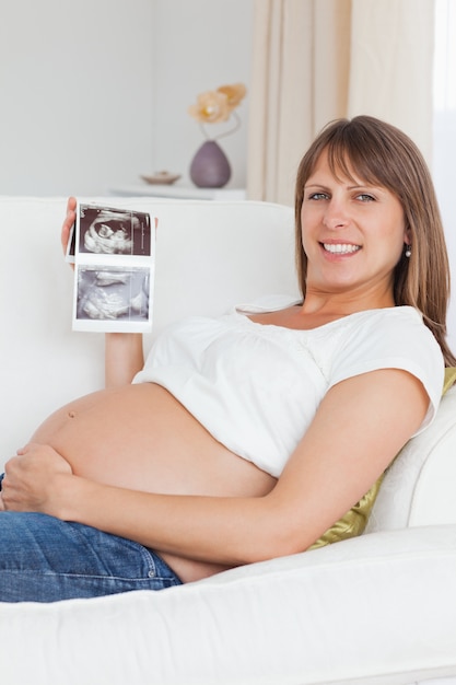 Chiuda in su di una donna incinta che mostra l&#39;ecografia del suo bambino