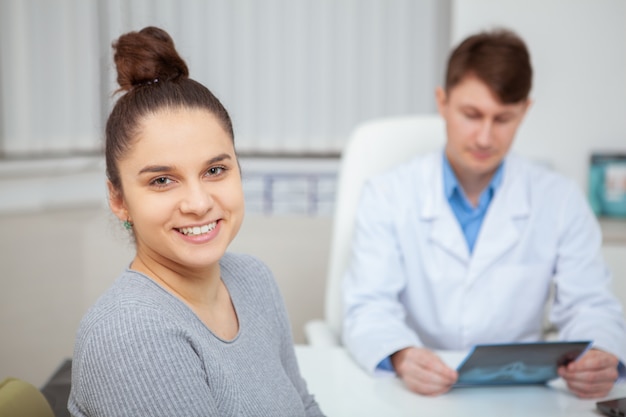 Chiuda in su di una giovane donna sana felice che sorride dopo appuntamento medico con il suo medico all'ospedale