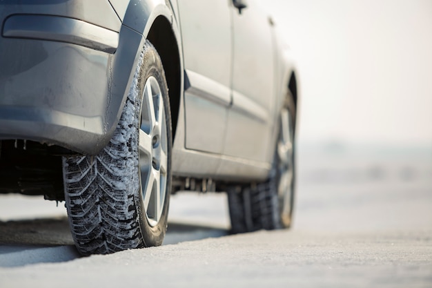 Chiuda in su di una gomma di automobile parcheggiata sulla strada nevosa il giorno di inverno. Concetto di trasporto e sicurezza.