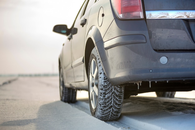 Chiuda in su di una gomma di automobile parcheggiata sulla strada nevosa il giorno di inverno. Concetto di trasporto e sicurezza.