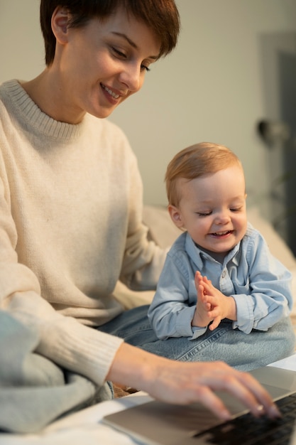 Chiuda in su donna sorridente e bambino con il computer portatile