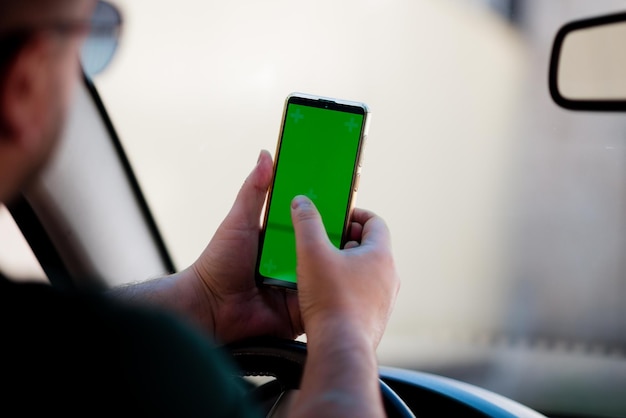 Chiuda in su mano uomo che utilizza smartphone con schermo verde che guida l'auto