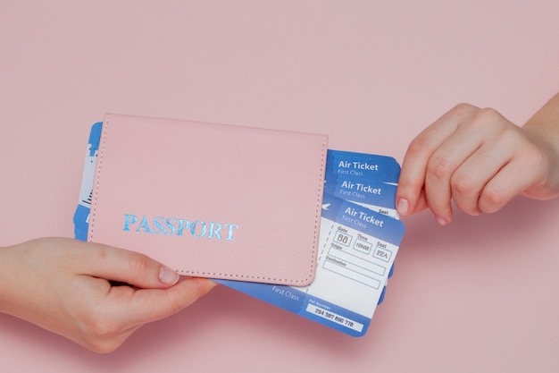 Chiuda in su orizzontale femminile turistico tenere in mano i biglietti per l'aereo con passaporto arancione sul rosa