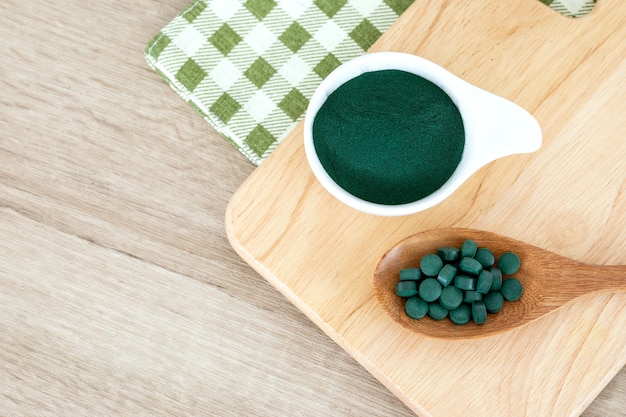 Chiuda in su una polvere di spirulina e pillole di spirulina in cucchiaio, una dieta superfood sana e una nutrizione della disintossicazione