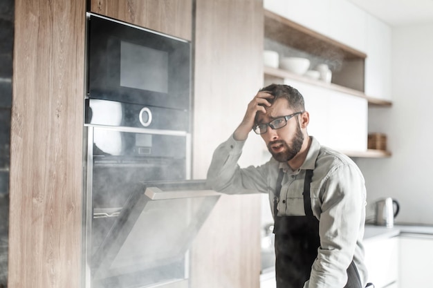 Chiuda in su uomo frustrato in piedi vicino a un forno elettrico