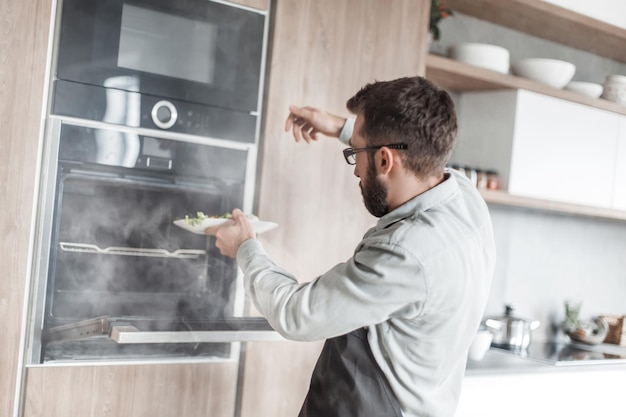 Chiuda in su uomo frustrato in piedi vicino a un forno elettrico