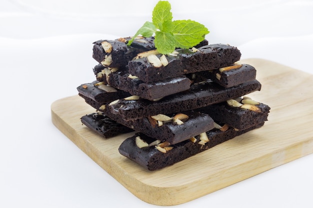 Chiuda su dei brownie del cioccolato del dolce con i dadi e la menta sul piatto di legno