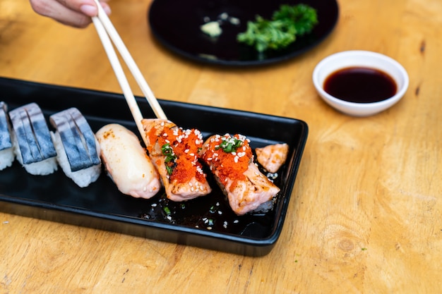 Chiuda su dei sushi messi con le bacchette e la soia sulla tavola di legno.