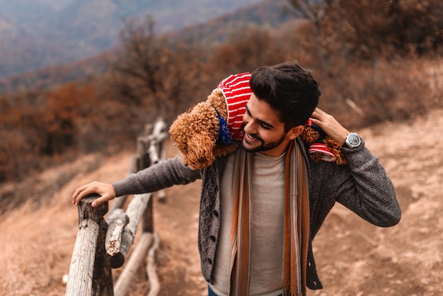 Chiuda su dell'uomo che tiene il suo cane sulle spalle mentre godono della natura. Tempo d'autunno.