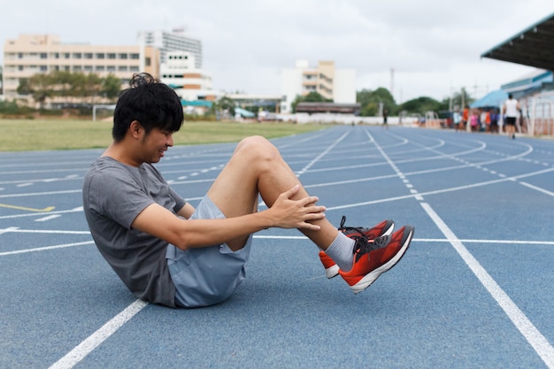 Chiuda su dell'uomo di sport che soffre con il dolore sugli sport che eseguono la ferita al ginocchio dopo avere corso. Lesione dal concetto di allenamento.