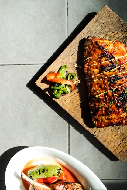 Chiuda su della bistecca delle costole di carne di maiale sulla designazione dell&#39;alimento del bordo di legno