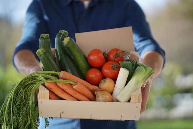 Chiuda su della cassa locale della tenuta dell&#39;agricoltore delle verdure stagionali organiche con il segno