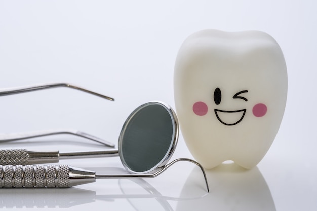 Chiuda su strumenti di Dental e denti di sorriso modellano su fondo bianco.