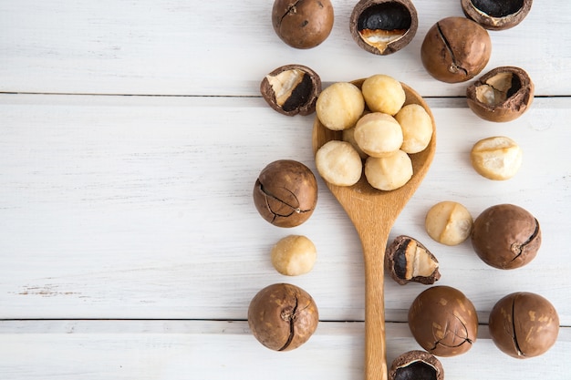 Chiuda sui dadi di macadamia su fondo di legno bianco