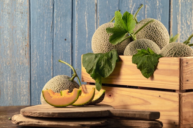 Chiuda sui meloni del cantalupo in scatola di legno sulla tavola di legno