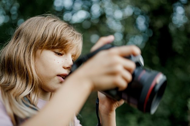 Chiuda sul bambino carino sta scattando foto fuori nella natura primaverile.