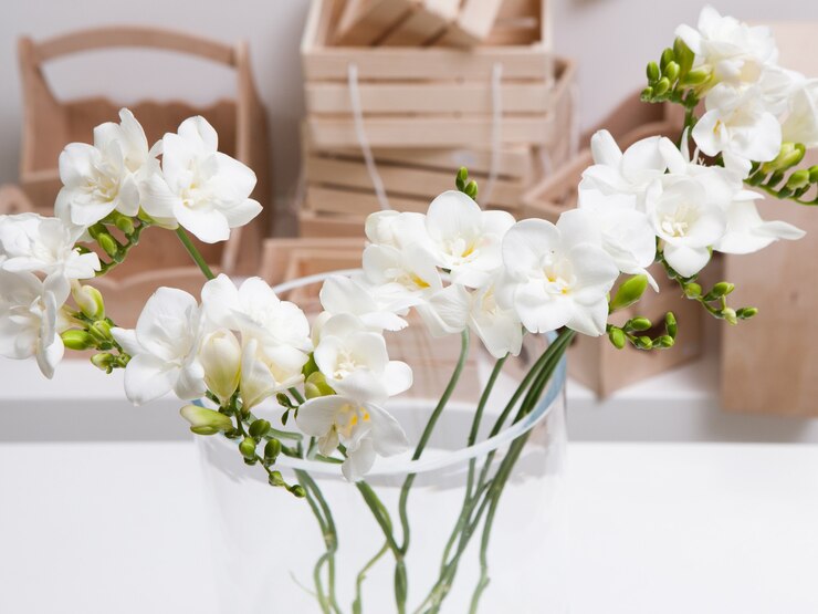Chiuda sul bel mazzo di orchidee bianche in vaso di vetro sul tavolo e sullo sfondo di scatole di legno. Laboratorio di floristica, composizione floreale per regali, tenerezza nel concetto di interni e decorazione