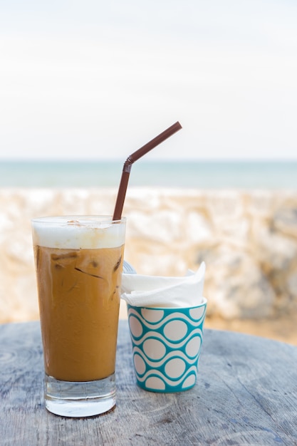 Chiuda sul caffè di ghiaccio sulla tavola di legno alla spiaggia