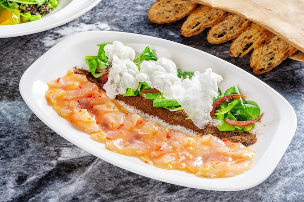 Chiuda sul ceviche del branzino servito in piatto sulla tavola di marmo