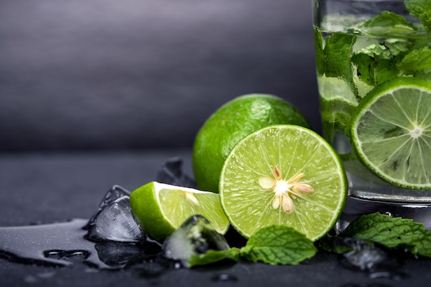 Chiuda sul cocktail fresco di mojito con la foglia fresca della menta e della calce su fondo di pietra nero