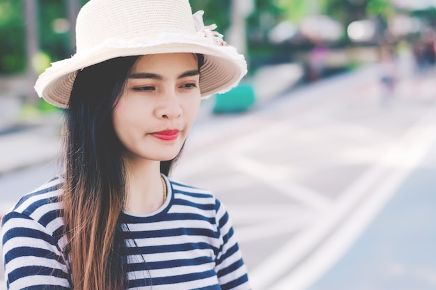 Chiuda sul colpo della giovane donna alla moda in cappello contro.