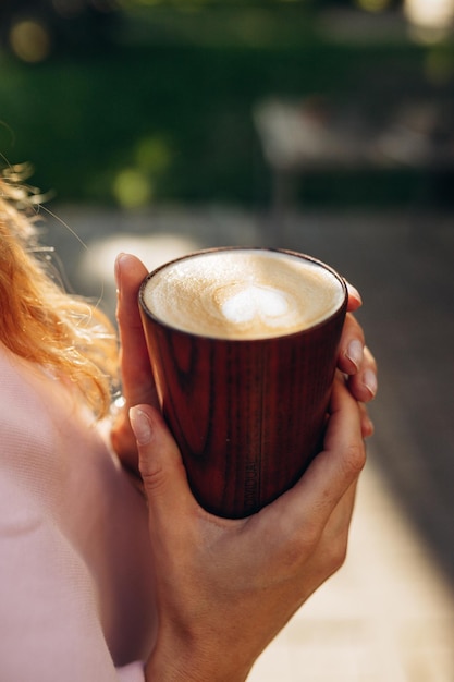 Chiuda sul colpo della ragazza che tiene una tazza di caffè nelle sue mani