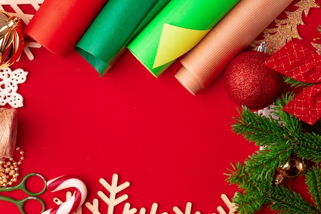 Chiuda sul colpo di carta da imballaggio e degli oggetti per natale che decora sul fondo rosso