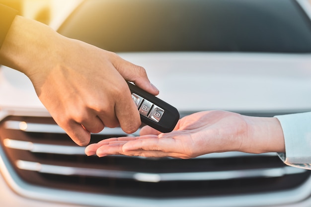 Chiuda sul concetto chiave dell'automobile della vendita chiave della tenuta della mano, dia e prenda l'automobile chiave