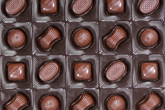 Chiuda sul fondo marrone della caramella di cioccolato. Assortimento di caramelle al cioccolato dolci nella scatola