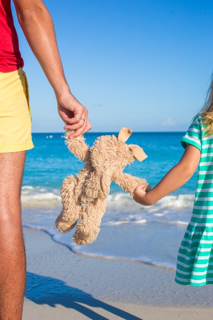 Chiuda sul giocattolo del coniglietto nelle mani della figlia e del papà sul fondo del mare