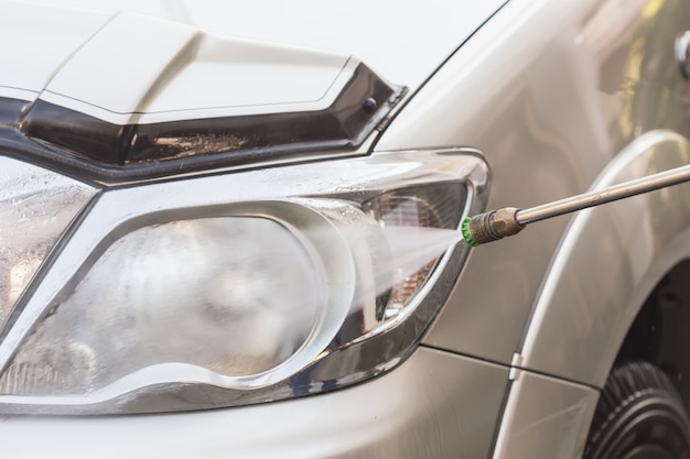 Chiuda sul lavaggio dell&#39;automobile con il getto di acqua ad alta pressione