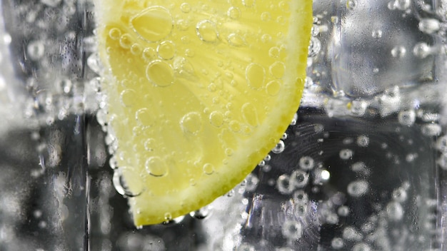 Chiuda sul limone, fetta della calce nelle bolle dell&#39;acqua di soda.