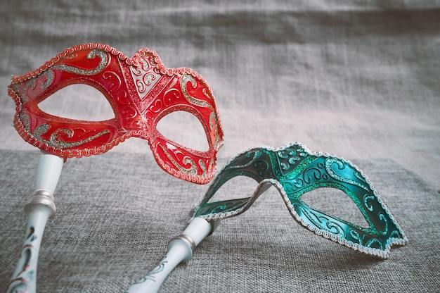 Chiuda sul masquerade veneziano rosso e verde, posto della maschera di carnevale sulla tela di sacco della tela da imballaggio