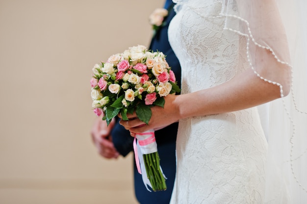 Chiuda sul mazzo di nozze di piccole rose a disposizione della sposa