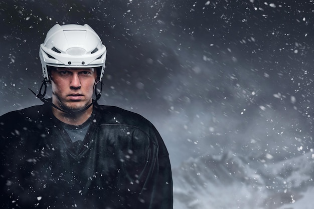 Chiuda sul ritratto all'aperto del giocatore di hockey in una tempesta di neve.