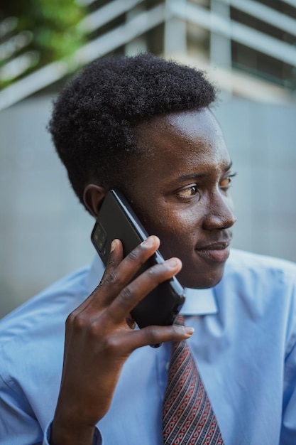 Chiuda sul ritratto dell'uomo d'affari africano che parla al telefono con un collega