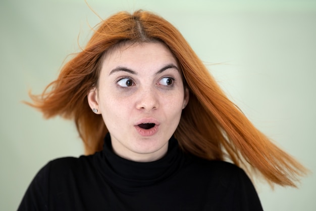 Chiuda sul ritratto della ragazza graziosa della testarossa con capelli ondulati lunghi che soffiano sul vento.