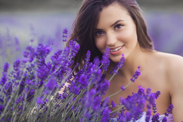 Chiuda sul ritratto di bella giovane donna nel giacimento della lavanda.