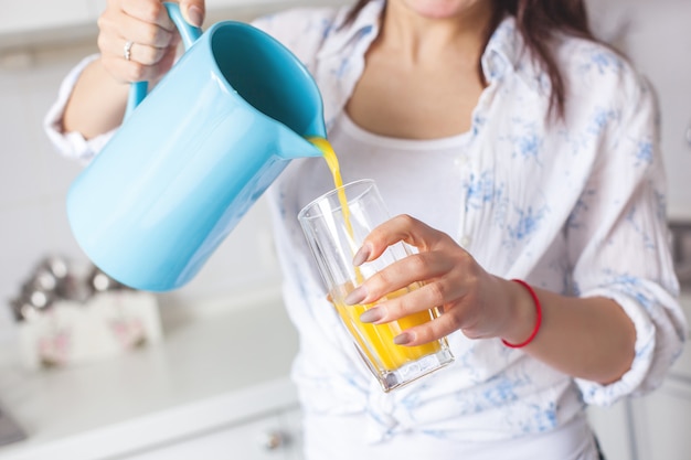 Chiuda sul ritratto di giovane donna attraente che beve il succo fresco